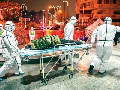 Personal médico que usa vestimenta especial traslada a una persona que presenta los síntomas del virus. Foto: AFP 