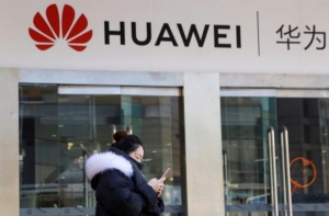 Una joven consulta su móvil delante de una tienda de Huawei. EFE/ Wu Hong